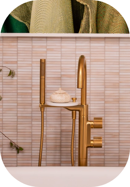 Gold faucet with shower head on a white shelf, part of an interior design.
